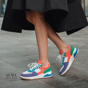 Una mujer con un vestido midi floral y tenis blancos en un ambiente urbano o en un parque. El look es casual y femenino, y la luz natural destaca los colores del vestido y el contraste relajado de (1)